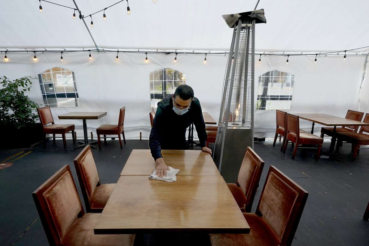 FILE - In this Nov. 19, 2020, file photo, Fabian Rodriguez cleans a table in an outdoor tented dining area of Tequila Museo Mayahuel restaurant, in Sacramento, Calif. Sales at restaurants and bars fell in October for the first time in six months.