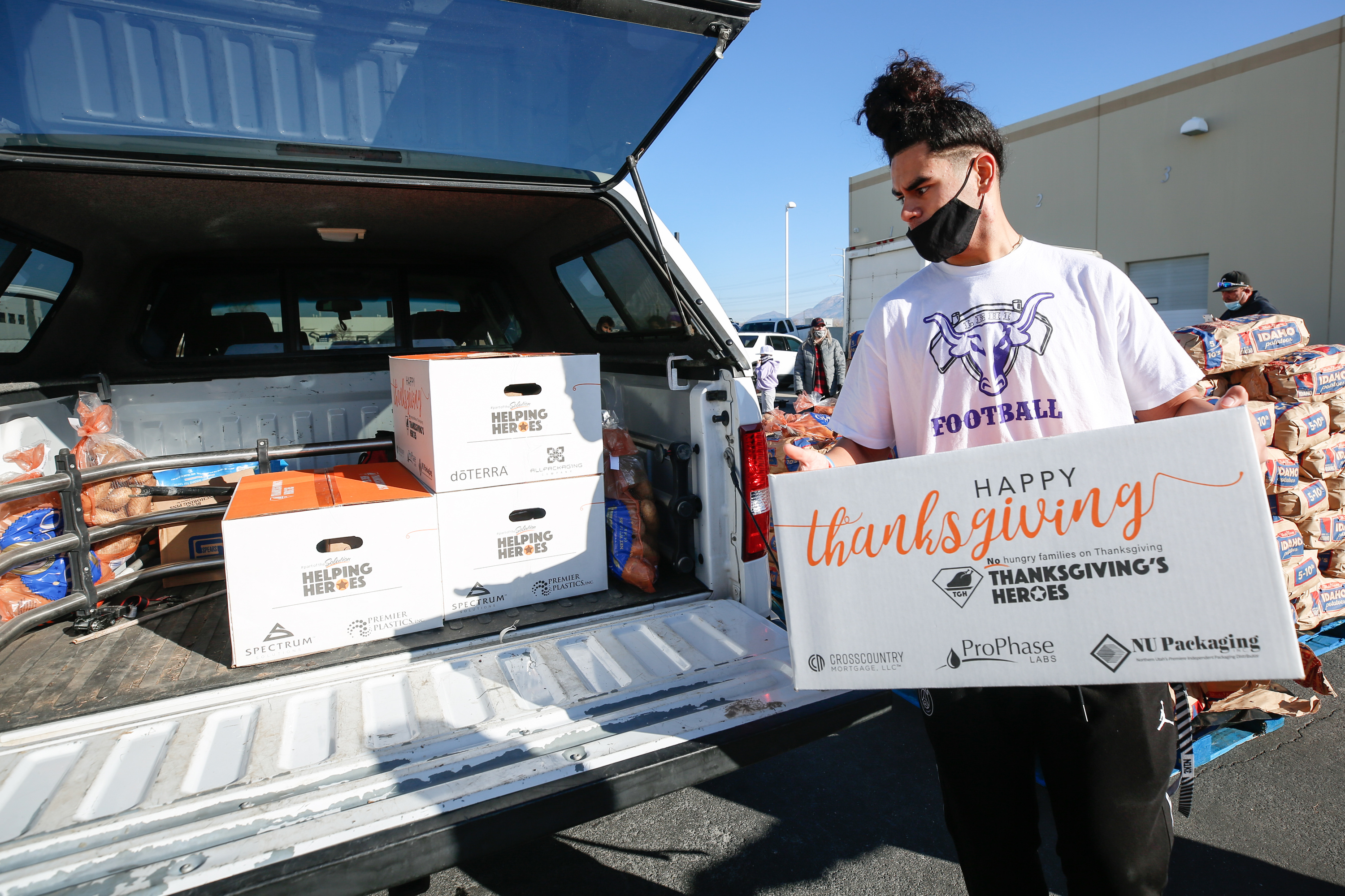Josiah Westover, a Thanksgiving's Heroes volunteer from Lehi High School, places a box of food into a car at Spectrum Solutions in Draper on Saturday, Nov. 21, 2020.