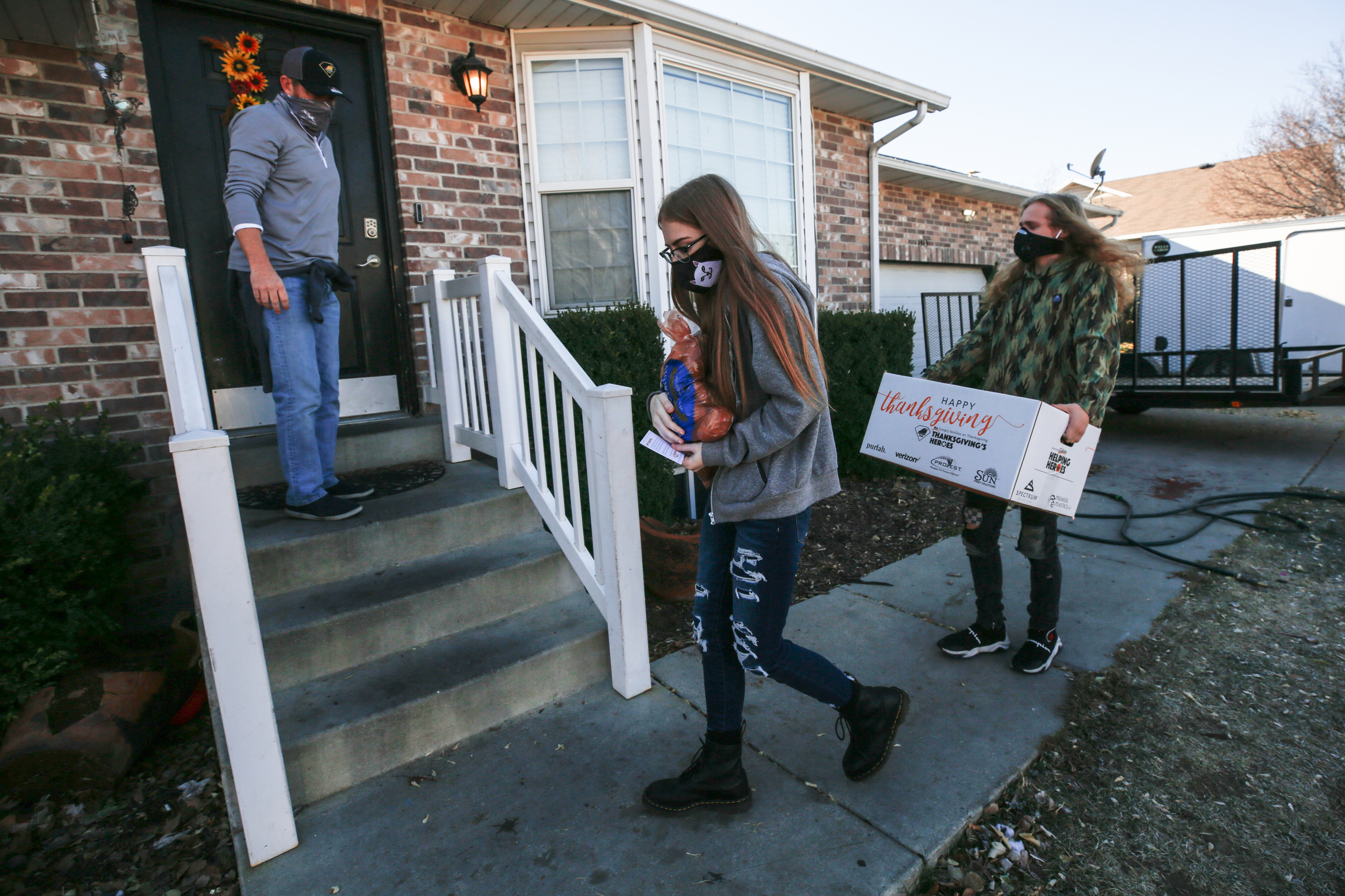 Thanksgiving's Heroes volunteers Lance Bush, left, his daughter, Brilee Bush, and her boyfriend, Kayden Jungst, deliver a box of food and a Thanksgiving card to a house in Draper on Saturday, Nov. 21, 2020.