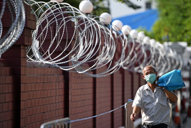 A man walks next to barbwire ahead of a mass rally to call for the ouster of Prime Minister Prayuth Chan-ocha's government and reforms in the monarchy, at the Crown Property Bureau in Bangkok, Thailand, November 24, 2020. REUTERS/Chalinee Thirasupa