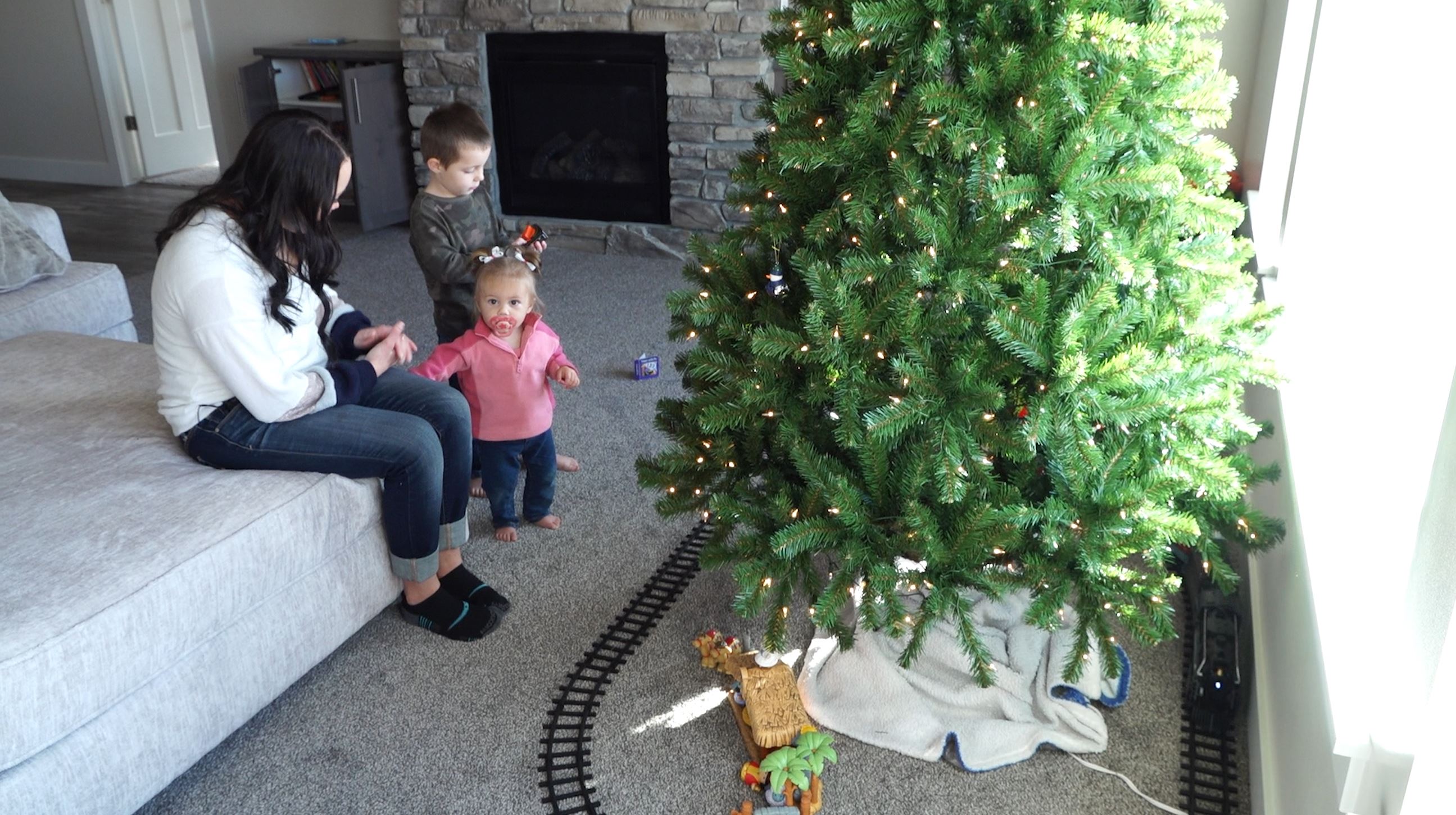 Kami Christensen helps her kids, Jed and McKenna, set up an electric train under their Christmas tree.