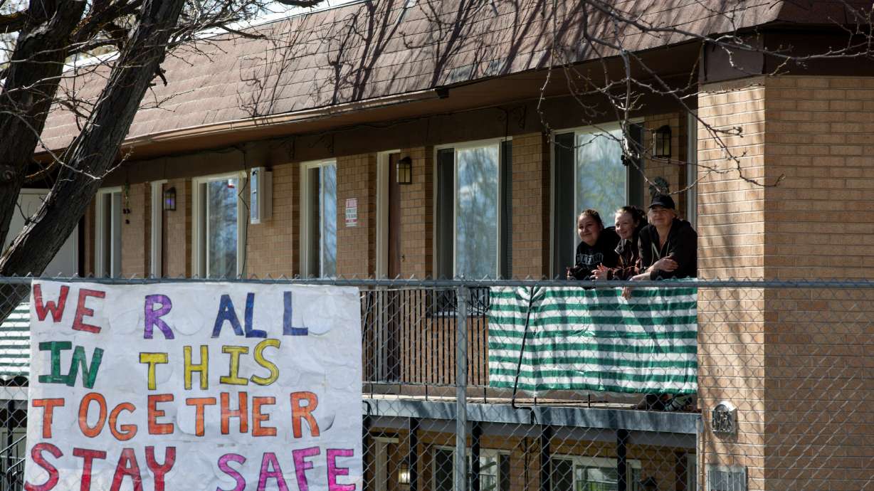 Matti Neer, McKenna Heugly and Sally Heugly pose by a sign in Murray on Sunday, April 12, 2020. After finding the poster wadded up on her apartment buildingâs lawn, Sally Heugly bolded the letters and reinforced the poster with her daughter McKenna, and hung it on the fence using zip ties, her neighbor Neer's idea. Sally Heugly said she thinks the sign was blown away by the wind after kids in neighboring homes hung it up down the road. âWhen I saw what it said it touched my heart. I was so happy to do it I said, âOh, I hope I did it justice for them,â I think itâs very important especially now,â she said.