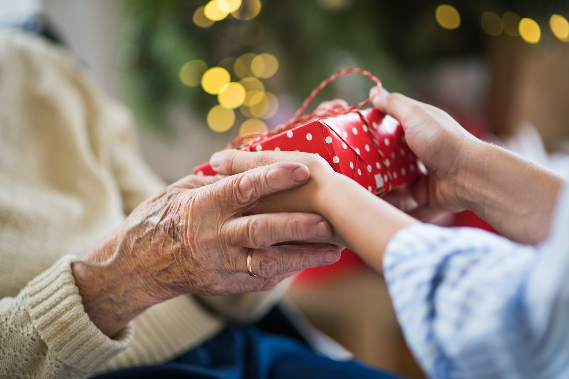 Close-up of hands of senior and young woman holding a present at Christmas.