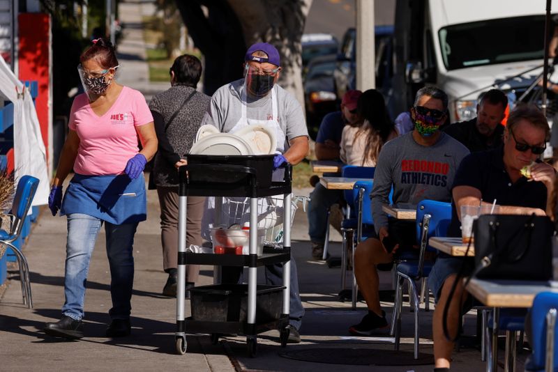 People eat along the sidewalk outside "Eat at Joes'' restaurant that continues to remain open following new coronavirus restrictions limiting restaurants to take-out only in Los Angeles County, during the outbreak of the coronavirus disease (COVID-19) in Redondo Beach, California, U.S., November 30, 2020.