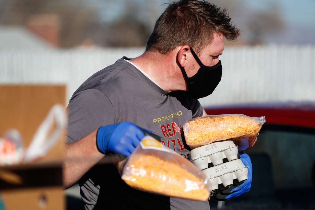 Robert Belshe carries cheese and egg during a food bank distribution event in the parking lot of a Church of Jesus Christ meetinghouse in West Jordan on Monday, Nov. 30, 2020.
