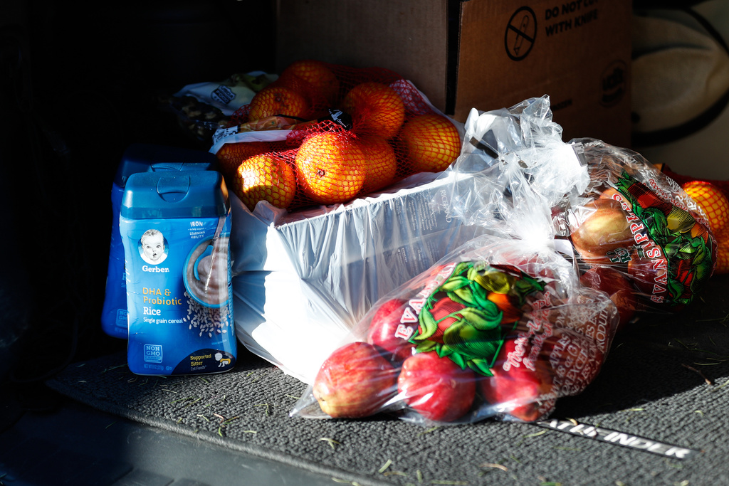 Fruit and baby food are placed in the trunk of a recipient’s car during a food bank distribution event in the parking lot of a Church of Jesus Christ meetinghouse in West Jordan on Monday, Nov. 30, 2020.