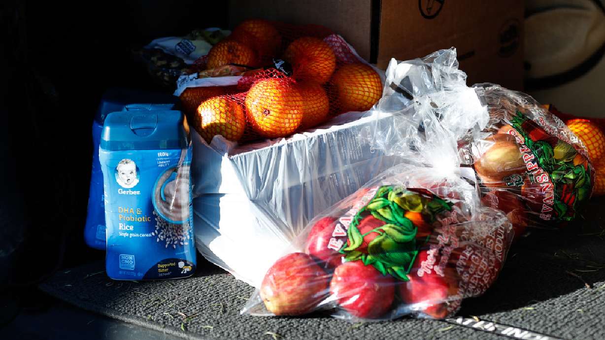 Fruit and baby food are placed in the trunk of a recipient’s car during a food bank distribution event in the parking lot of a Church of Jesus Christ meetinghouse in West Jordan on Monday, Nov. 30, 2020.