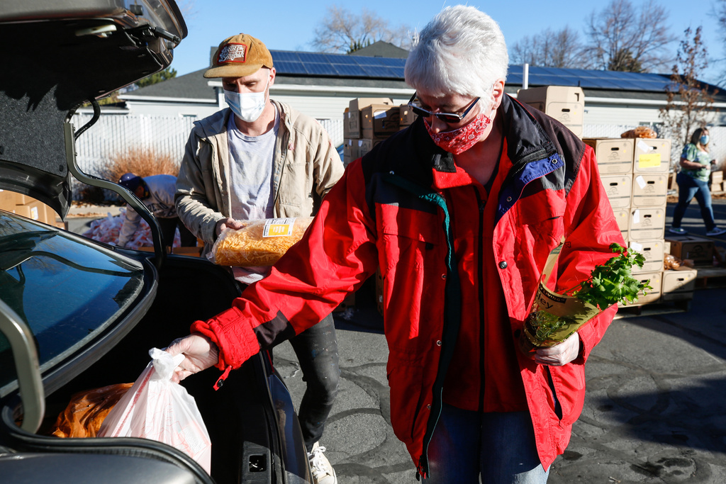Austin Namba, left, and Tina Maxfield put food into a recipient's car during a food bank distribution event in the parking lot of a Church of Jesus Christ meetinghouse in West Jordan on Monday, Nov. 30, 2020.