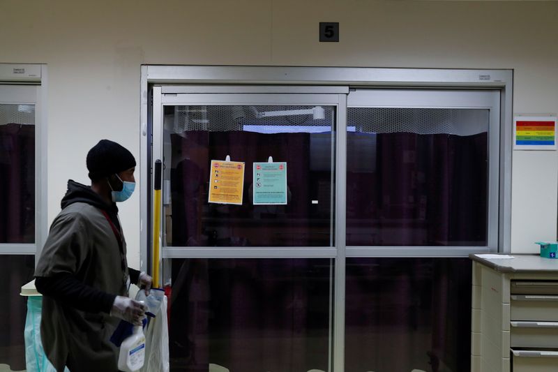 FILE PHOTO: A housekeeper walks by the isolation room of a coronavirus disease (COVID-19) positive patient inside the emergency room bed at Roseland Community Hospital on the South Side of Chicago, Illinois, U.S., December 2, 2020. REUTERS/Shannon Stapleton/File Photo