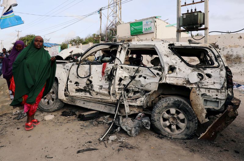 FILE PHOTO: Somali women walk near the wreckage of a car destroyed at the scene of a militant attack at the Elite Hotel in Lido beach, in Mogadishu, Somalia August 17, 2020. REUTERS/Feisal Omar/File Photo
