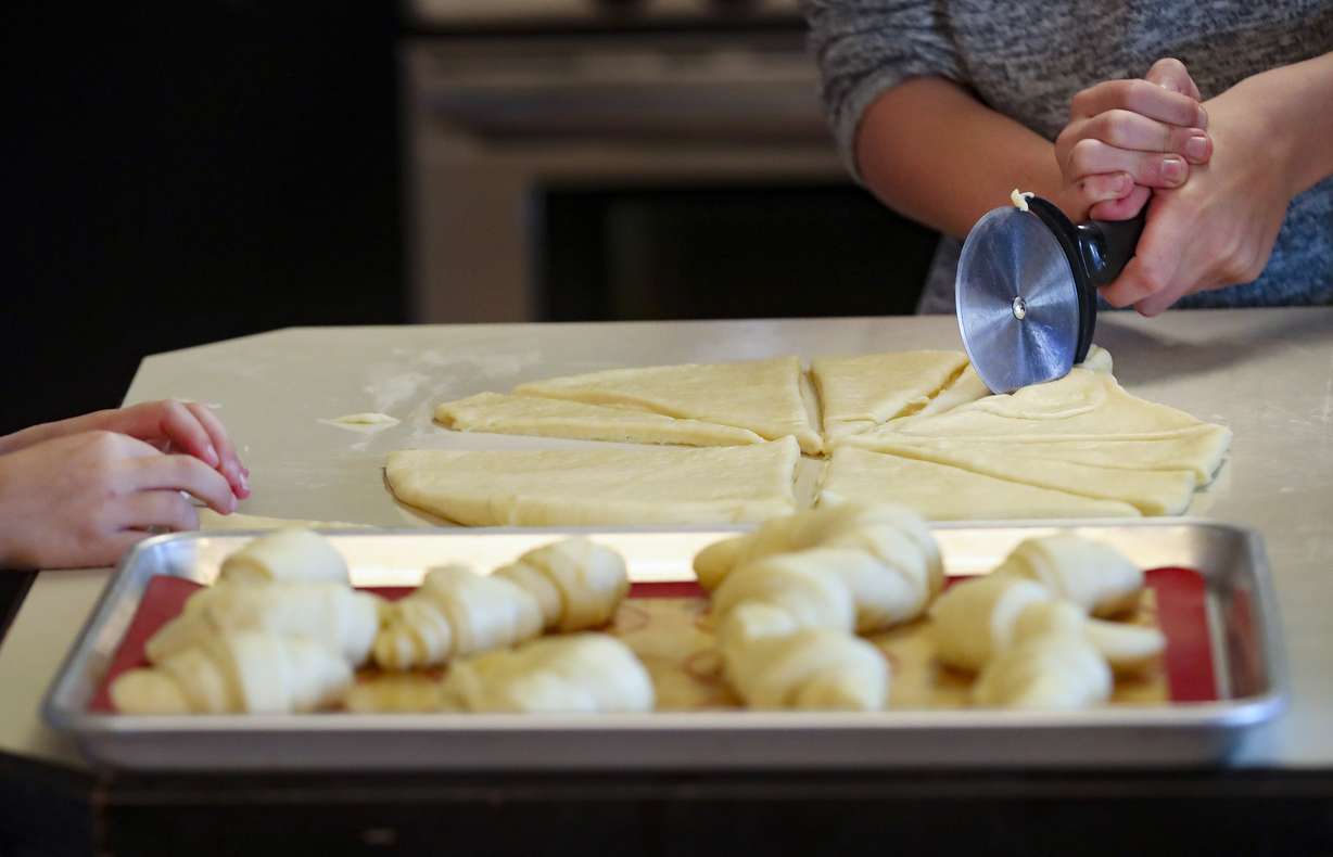 Henry White cuts dough as he makes Thanksgiving rolls with sisters Penny and Ellie and mom Emily in the kitchen of their home in Holladay on Wednesday, Nov. 25, 2020. The family started a bakery two years ago and has been baking loaves of bread every week, fulfilling neighbors' orders. This year, the family is donating proceeds from Thanksgiving roll sales to foster care agency Brighter Futures to help pay for kids' Christmas presents after Utah and Salt Lake counties notified the agency they can't give it funding for gifts this year.