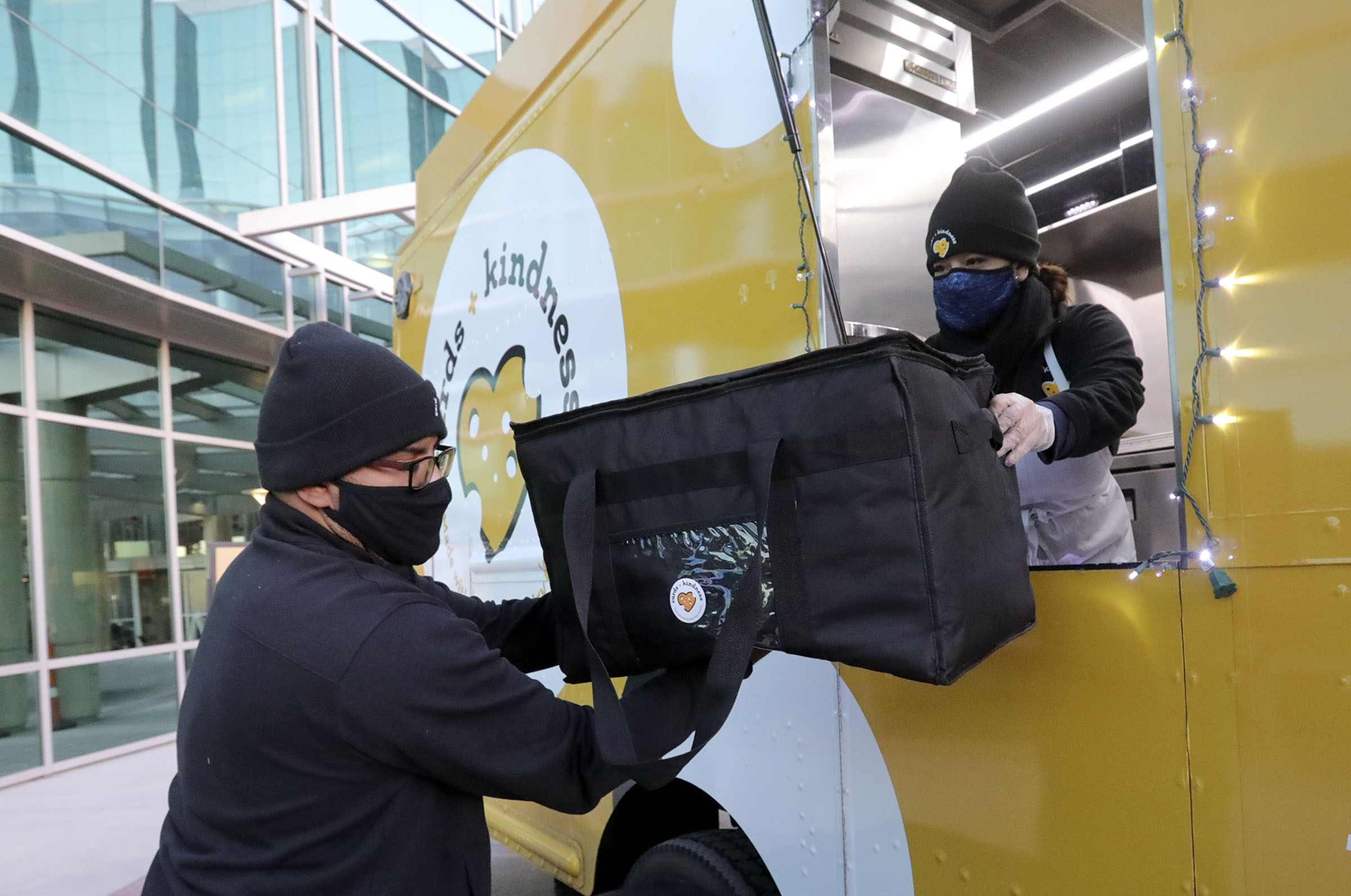 Sid Burgos, Curds + Kindness tour manager, takes the last batch of grilled cheese sandwiches from Lissette Torres, Curds + Kindness brand ambassador, to deliver to front-line workers at the Huntsman Cancer Institute in Salt Lake City on Thursday, Dec. 3, 2020.