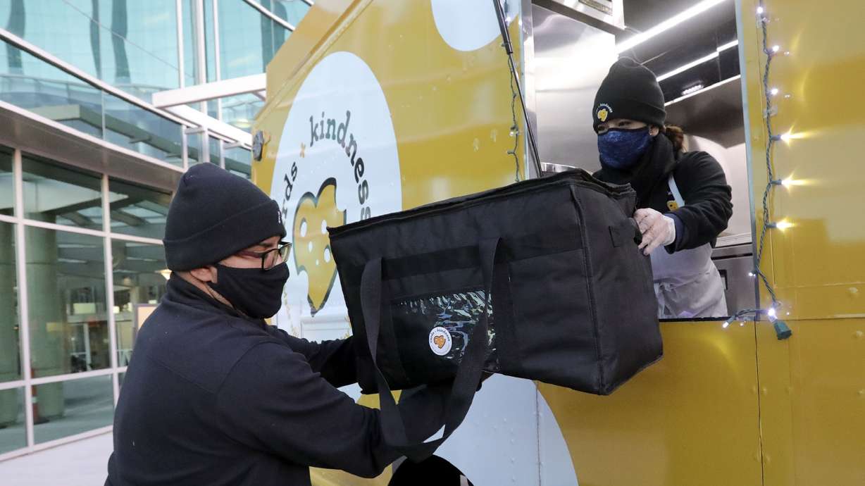 Sid Burgos, Curds + Kindness tour manager, takes the last batch of grilled cheese sandwiches from Lissette Torres, Curds + Kindness brand ambassador, to deliver to front-line workers at the Huntsman Cancer Institute in Salt Lake City on Thursday, Dec. 3, 2020.