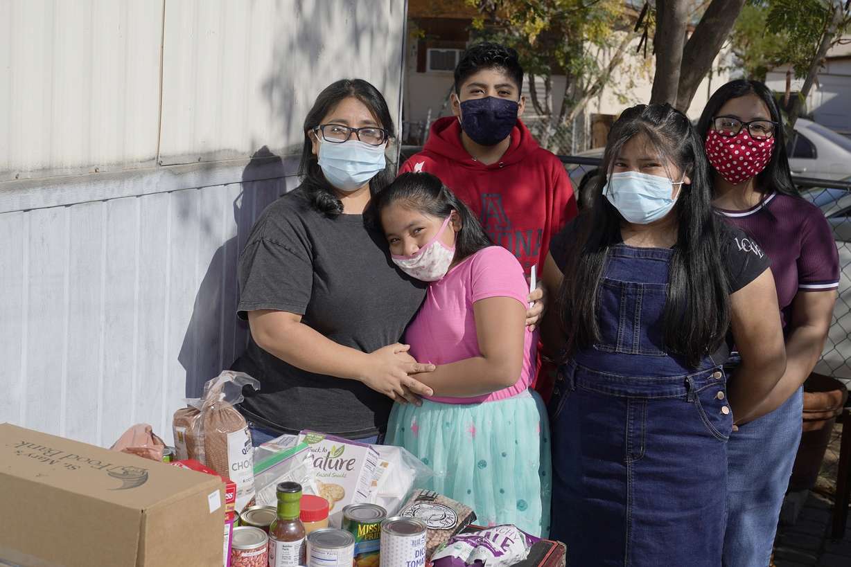 From left, Abigail Leocadio, stands with her children, Areli, 9, Eliel, 12, Zeret, 10, and Samai, 15, after a delivery from the Emmaus House food pantry Saturday, Nov. 14, 2020, in Phoenix. Leocadio says the food provides less than half of what her family eats in four weeks, but significantly reduces their monthly bill. Before the pandemic, the family was saving to buy a house, but that money has been wiped out.