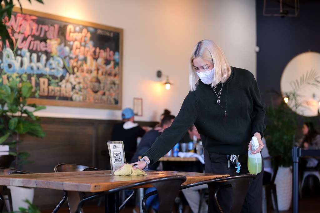 Allie Chernosky cleans a table and chairs at Oak Wood Fire Kitchen in Draper on Tuesday, Dec. 8, 2020.