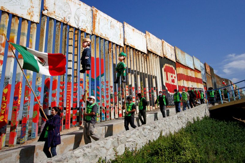FILE PHOTO: Migrants and members of civil society hold pinatas in the image of U.S. President Donald Trump and a border patrol officer during a protest against stalled asylum claims and the building of the wall, at the border fence between Mexico and the U.S. in Tijuana, Mexico October 31, 2020. REUTERS/Jorge Duenes