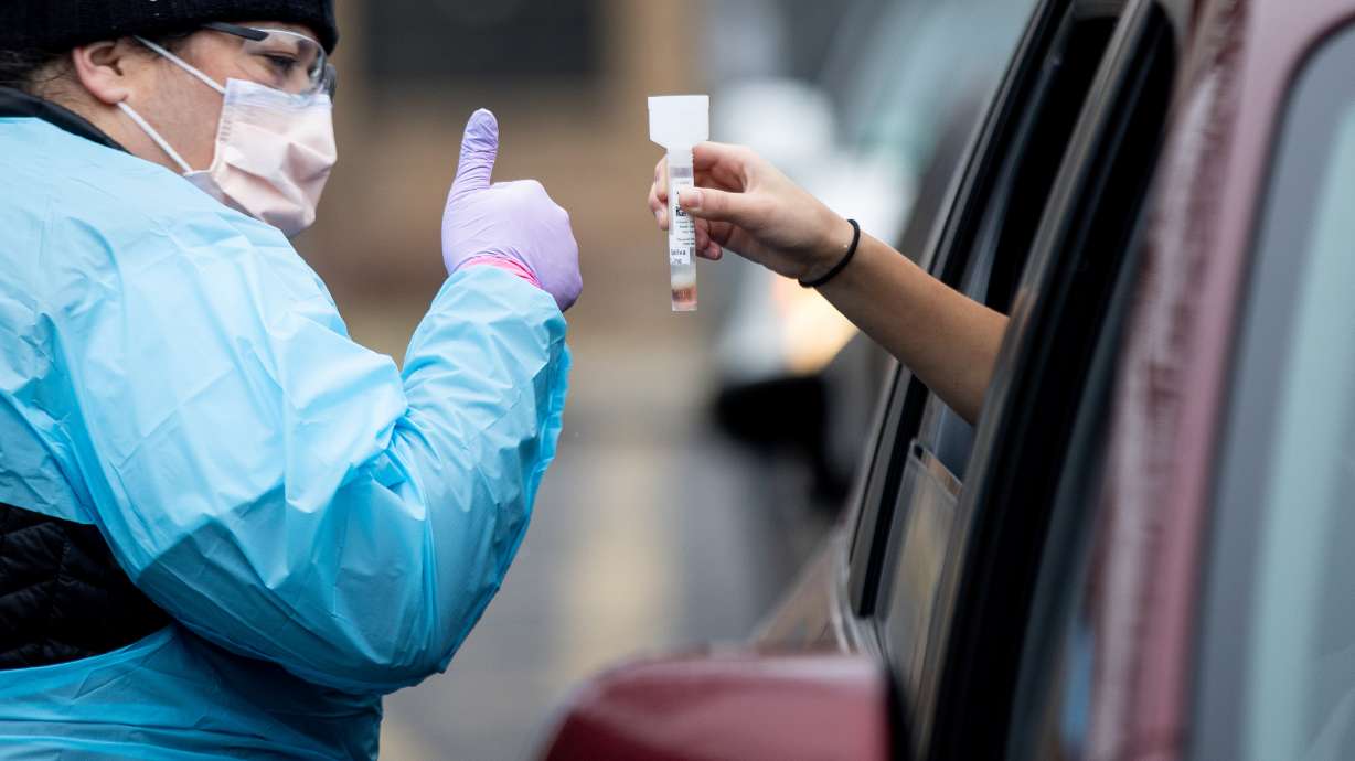 Registered nurse Amy Wilcox gives a thumbs-up as Charity Thompson, 13, takes a COVID-19 test at a drive-thru test center at Rice-Eccles Stadium in Salt Lake City on Friday, Dec. 11, 2020.