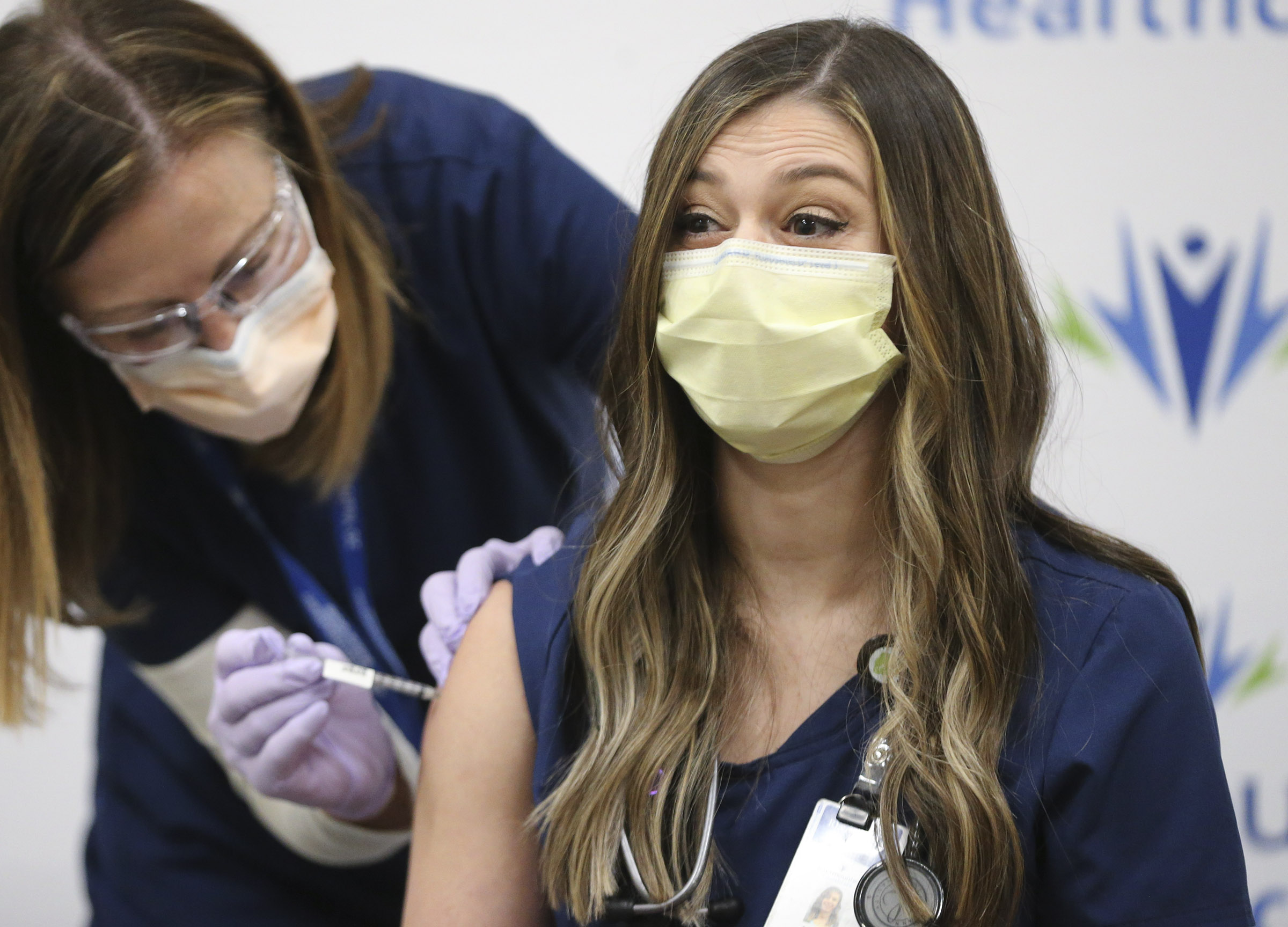 Registered nurse Amanda Vicchrilli, right, reacts as fellow registered nurse Julie Nelson vaccinates her for COVID-19 at LDS Hospital in Salt Lake City on Tuesday, Dec. 15, 2020.