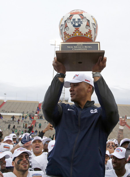 Utah State interim head coach Frank Maile lifts the trophy after his team's 52-13 victory over North Texas in the New Mexico Bowl NCAA college football game in Albuquerque, N.M., Saturday, Dec. 15, 2018.