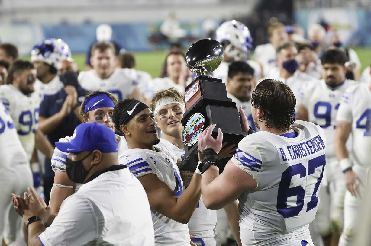 BYU Cougars quarterback Zach Wilson (1), running back Lopini Katoa (4) and offensive lineman Brady Christensen (67) hoist the trophy after the Boca Raton Bowl in Boca Raton, Fla., on Tuesday, Dec. 22, 2020. BYU beat UCF 49-23.