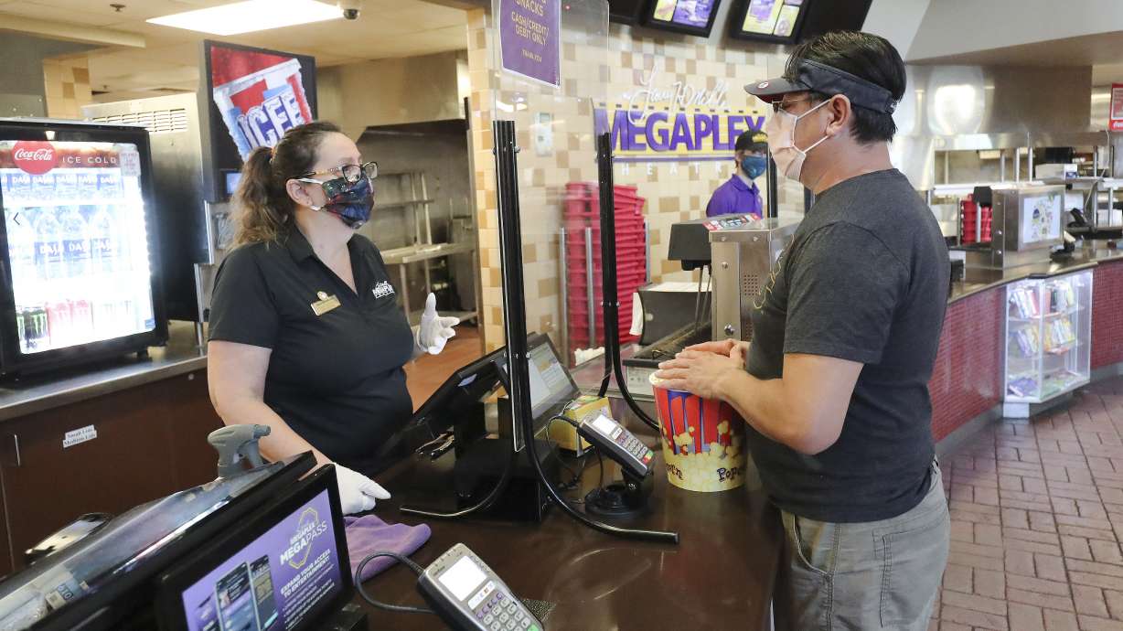 Jorge Robles, right, buys popcorn from employee Celia Santiago at the Megaplex Theatres at Valley Fair Mall in West Valley City on Thursday, June 18, 2020. After three months of temporary closure due to COVID-19 restrictions, Larry H. Miller Megaplex Theatres are resuming modified business operations.