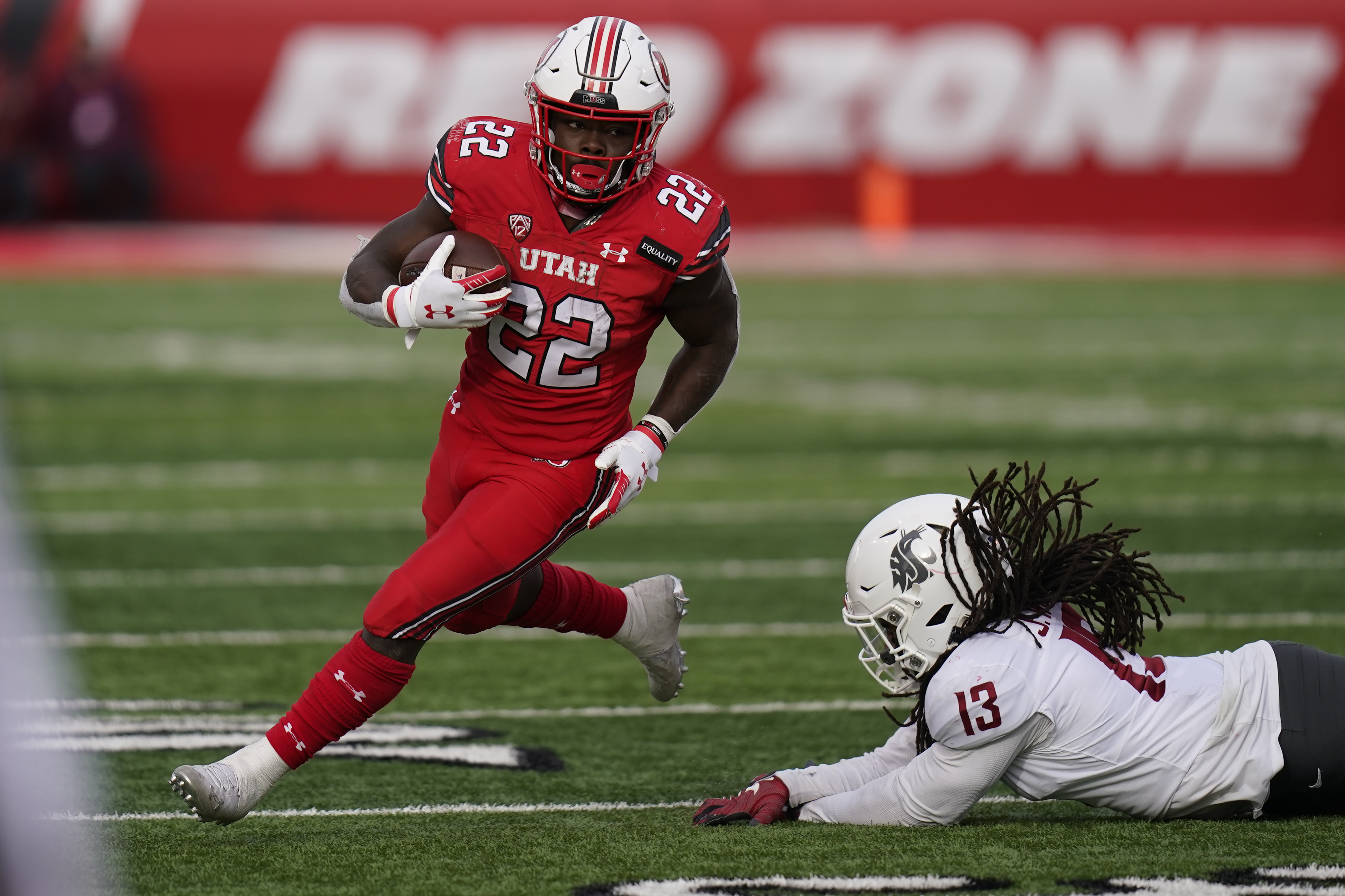 FILE - In this Dec. 19, 2020, file photo, Utah running back Ty Jordan (22) runs for a score as he eludes a tackle by Washington State linebacker Jahad Woods (13) during the second half of an NCAA college football game, in Salt Lake City.   Authorities say Jordan died at a hospital in the Dallas area after accidently shooting himself. University officials announced Ty Jordan’s death Saturday, the day after he was named Pac-12’s newcomer of the year.