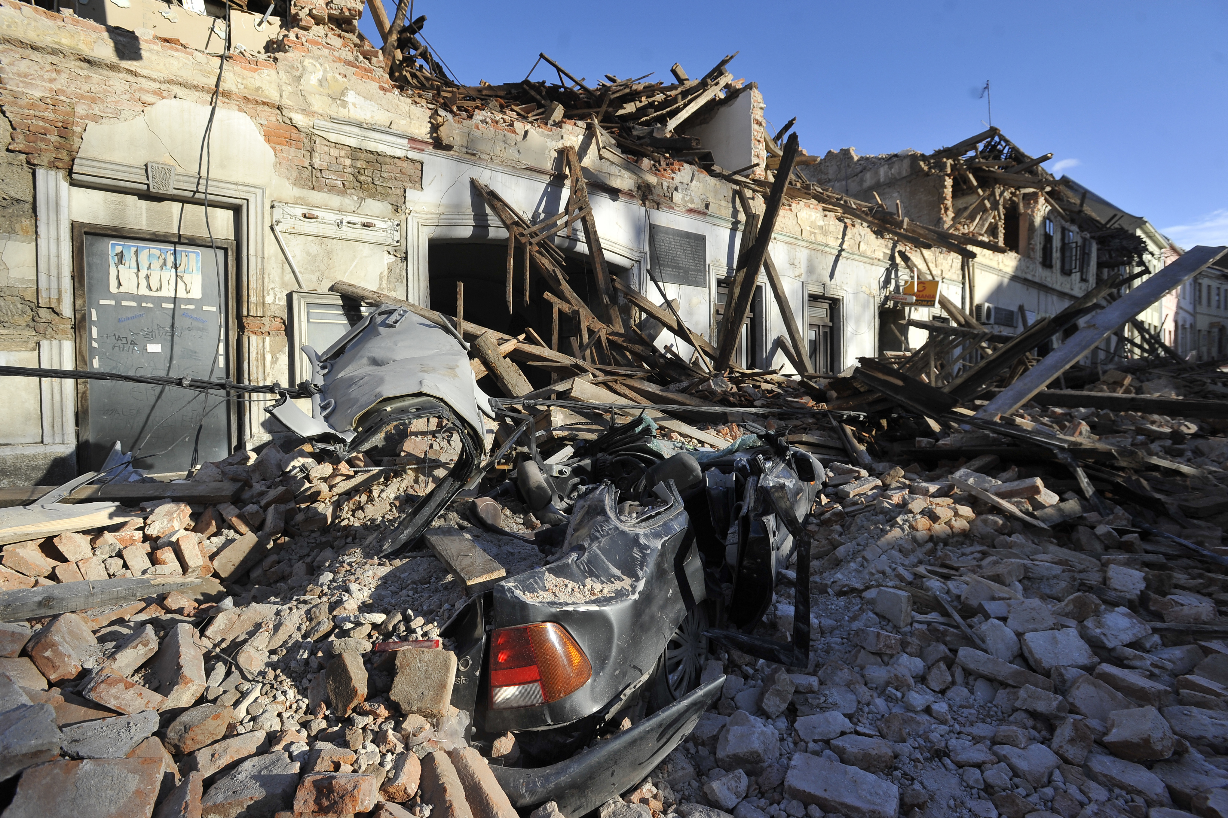 A view of remains of a car covered by debris and buildings damaged in an earthquake in Petrinja, Croatia, Tuesday, Dec. 29, 2020.