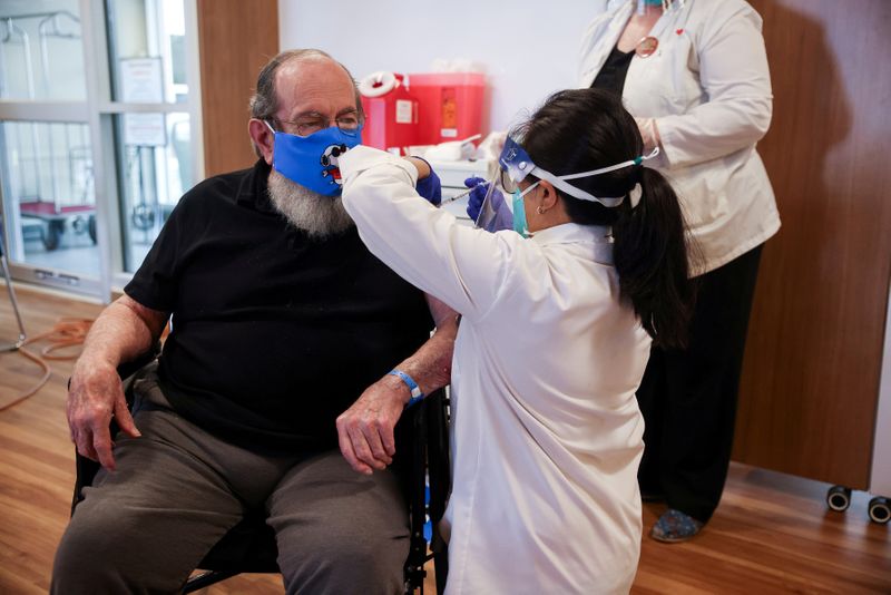 FILE PHOTO: U.S. Air Force veteran Robert Aucoin, 78, receives a coronavirus disease (COVID-19) vaccine dose at the Soldiers' Home in Holyoke, Massachusetts, U.S. December 29, 2020. Hoang ‘Leon’ Nguyen/The Republican/Pool via REUTERS