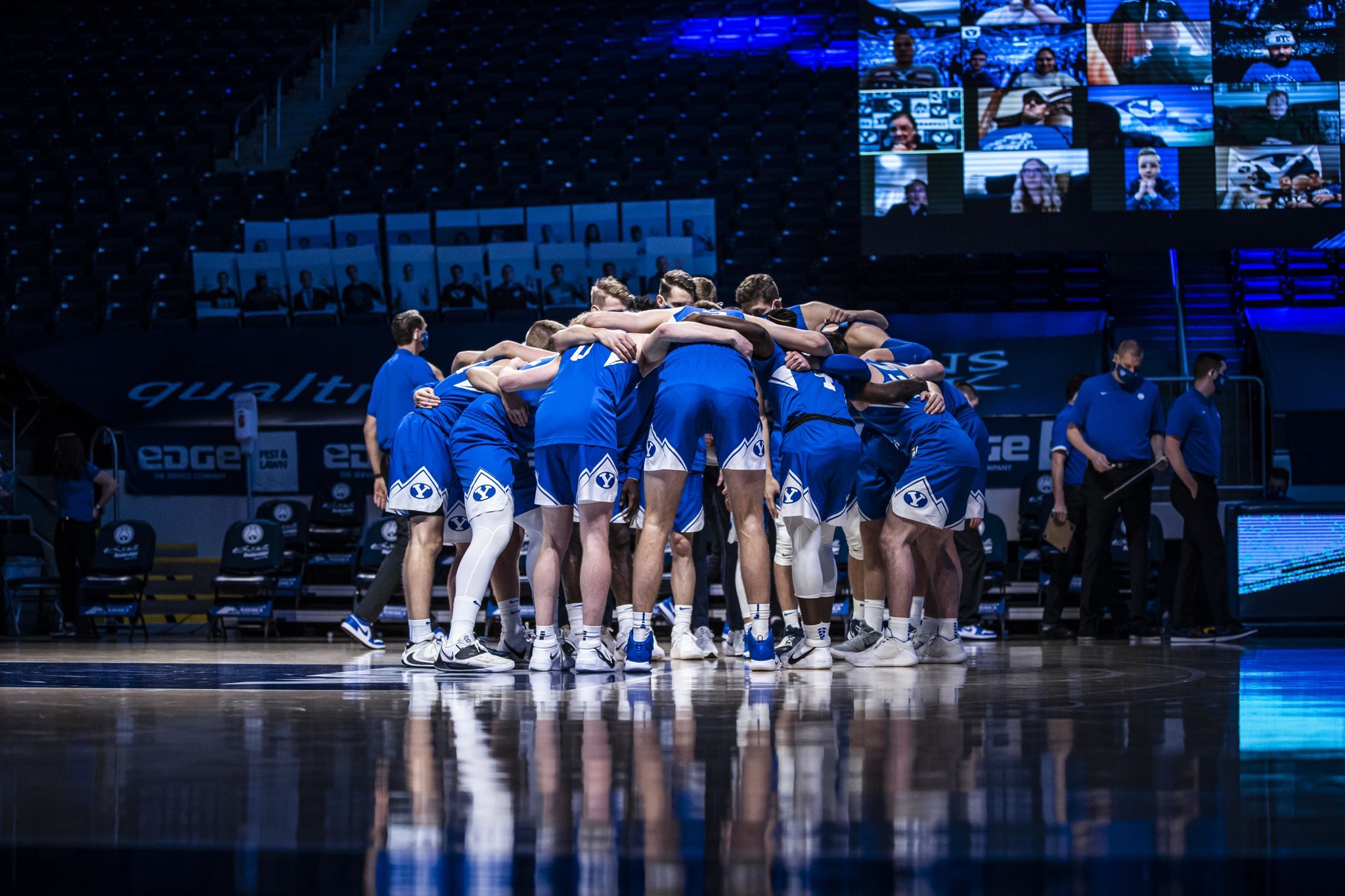 BYU basketball huddles up before a game against Utah wearing all-royal blue uniforms.