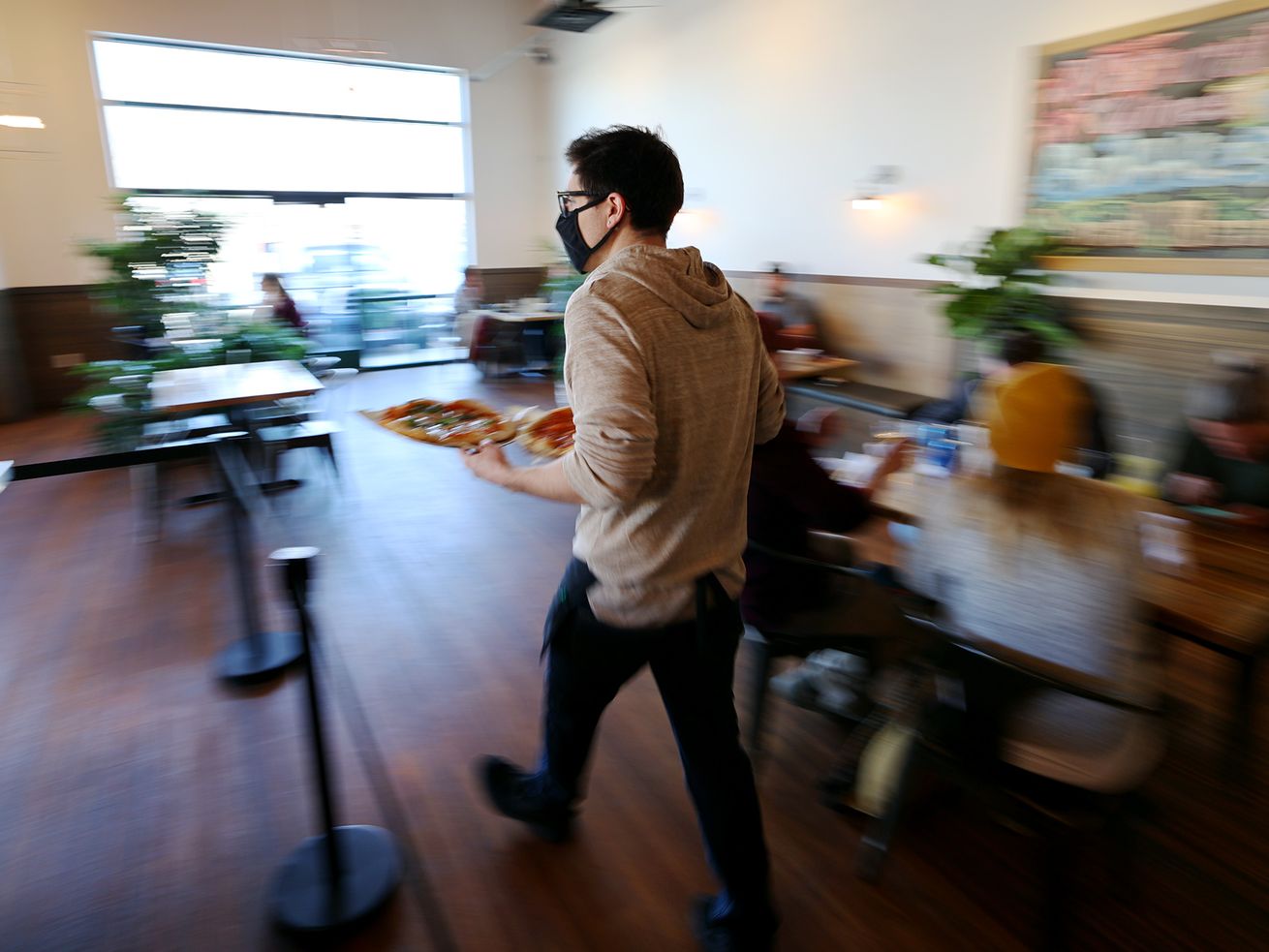 Server Shade Hammand takes an order out to a table at
Oak Wood Fire Kitchen in Draper on Tuesday, Dec. 8, 2020.