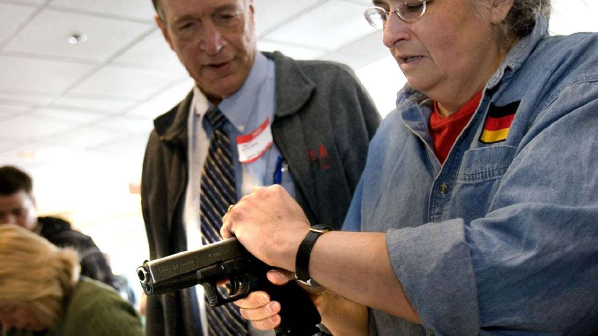 Tery Binkerd, right, holds a hand gun with assistance
from Jim McCarthy, a Utah Concealed Carry Permit Instructor, during
a free concealed carry class in 2012.