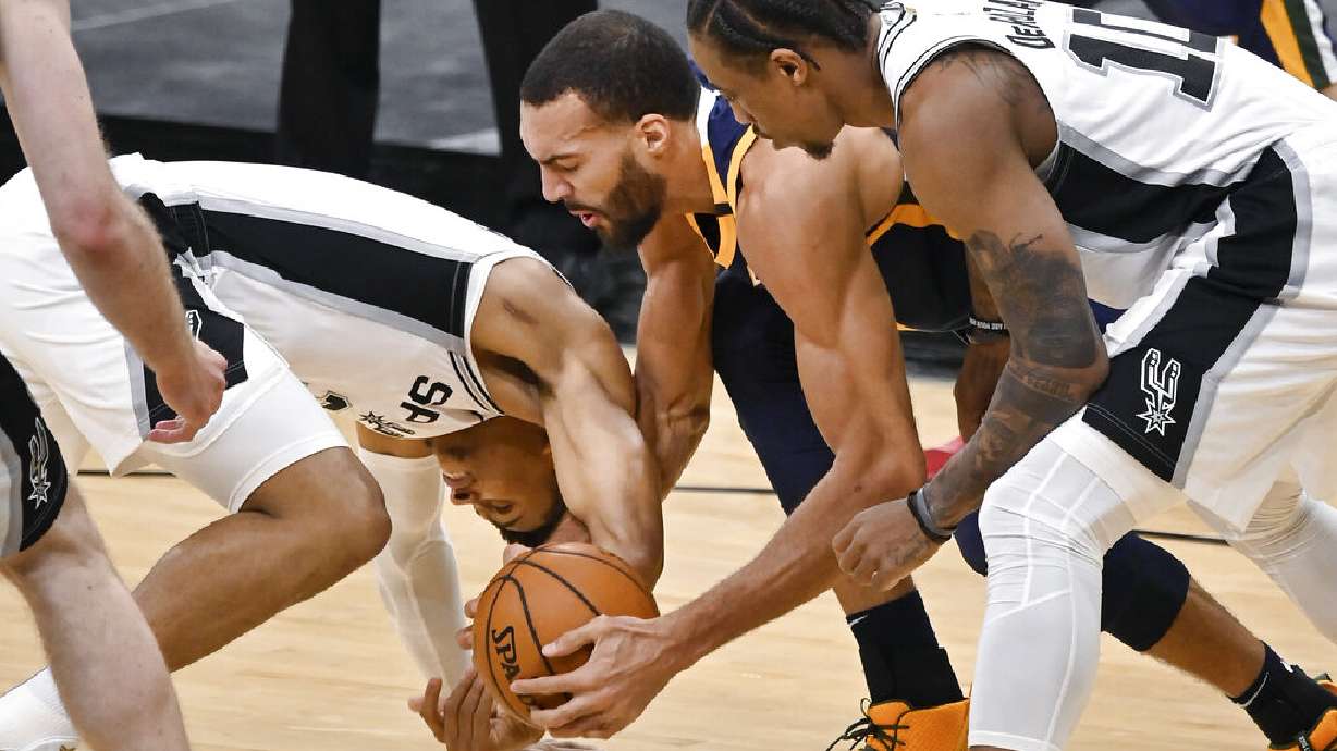 Utah Jazz's Rudy Gobert, center, battles San Antonio Spurs' Keldon Johnson, left, and DeMar DeRozan for possession during the first half of an NBA basketball game, Sunday, Jan. 3, 2021, in San Antonio. (AP Photo/Darren Abate)