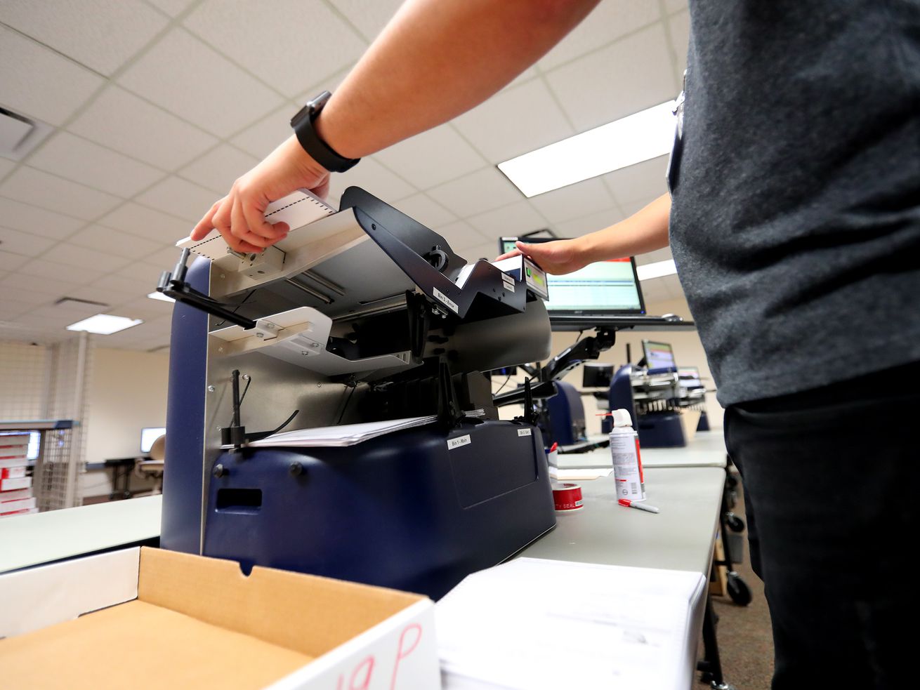 Carson Adams, a temporary election coordinator, scans
ballots at the Salt Lake County Government Center in Salt Lake City
on Wednesday, Aug. 7, 2019.