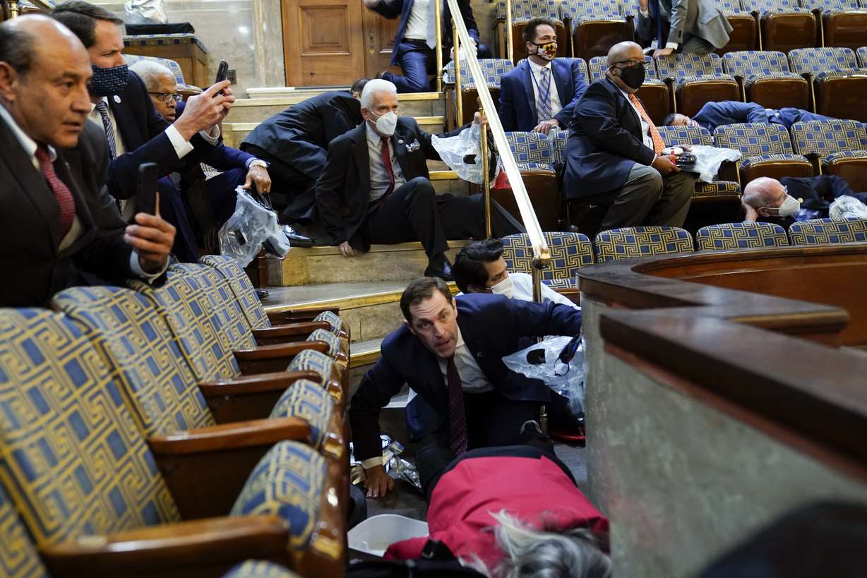 People shelter in the House gallery as protesters try to break into the House Chamber at the U.S. Capitol on Wednesday, Jan. 6, 2021, in Washington.