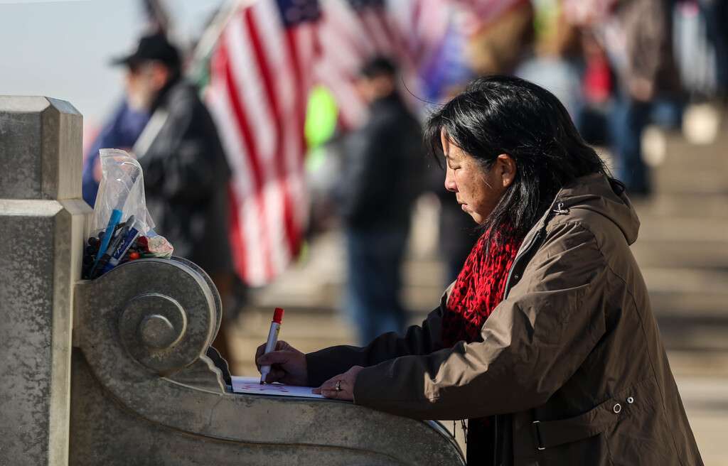 Susan, who did not provide a last name, writes on a sign “Stolen: My right to a fair legal election” near the steps of the Capitol in Salt Lake City on Wednesday, Jan. 6, 2021.