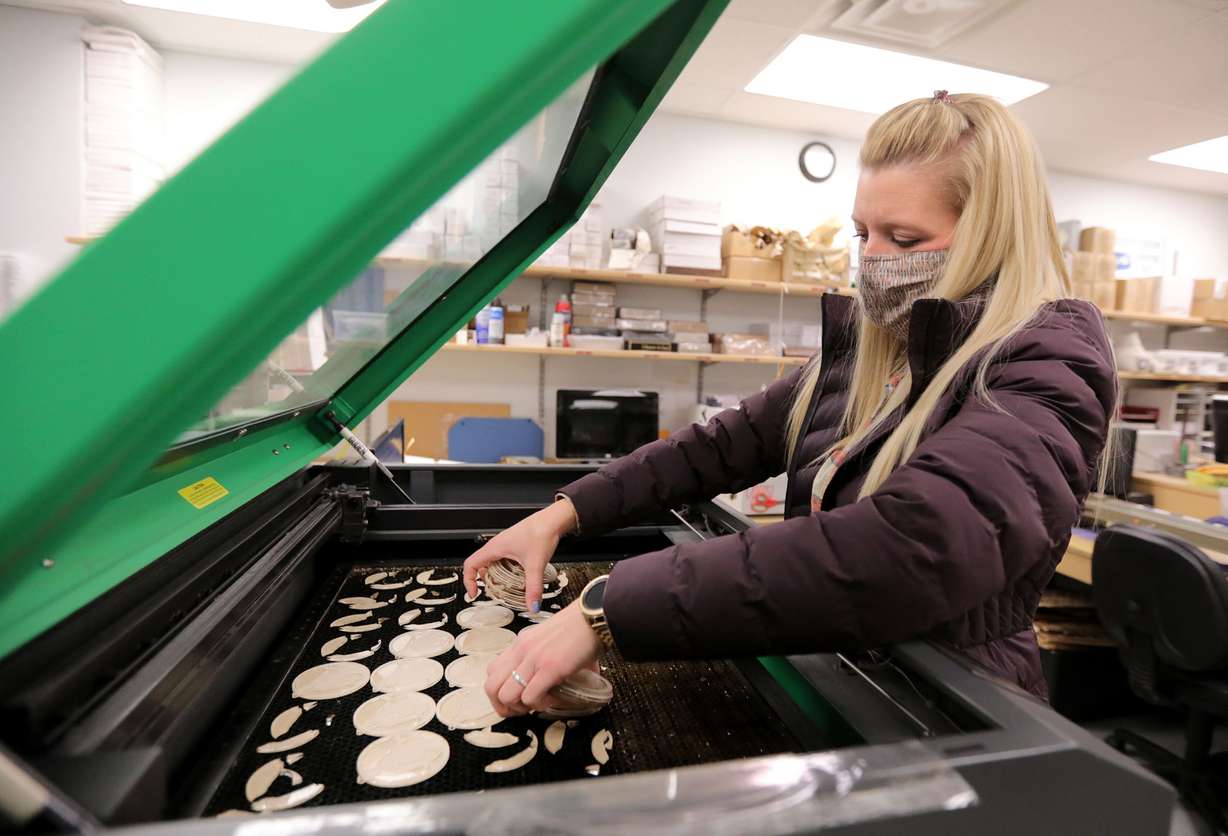 Mandy Littlefield, Naag Tag designer, pulls ornaments out of a laser engraver cutter at Naag Tag in West Jordan on Wednesday, Jan. 6, 2021.