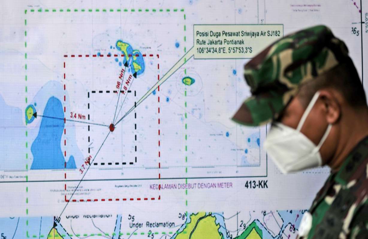 An Indonesian soldier walks past a map showing the location where a Sriwijaya Air passenger jet has lost contact with air traffic controllers shortly after taking off, at the search and rescue command center at Tanjung Priok Port in Jakarta, Indonesia, Sunday, Jan. 10, 2021. The Boeing 737-500 took off from Jakarta for Pontianak, the capital of West Kalimantan province on Indonesia's Borneo island, and lost contact with the control tower a few moments later.