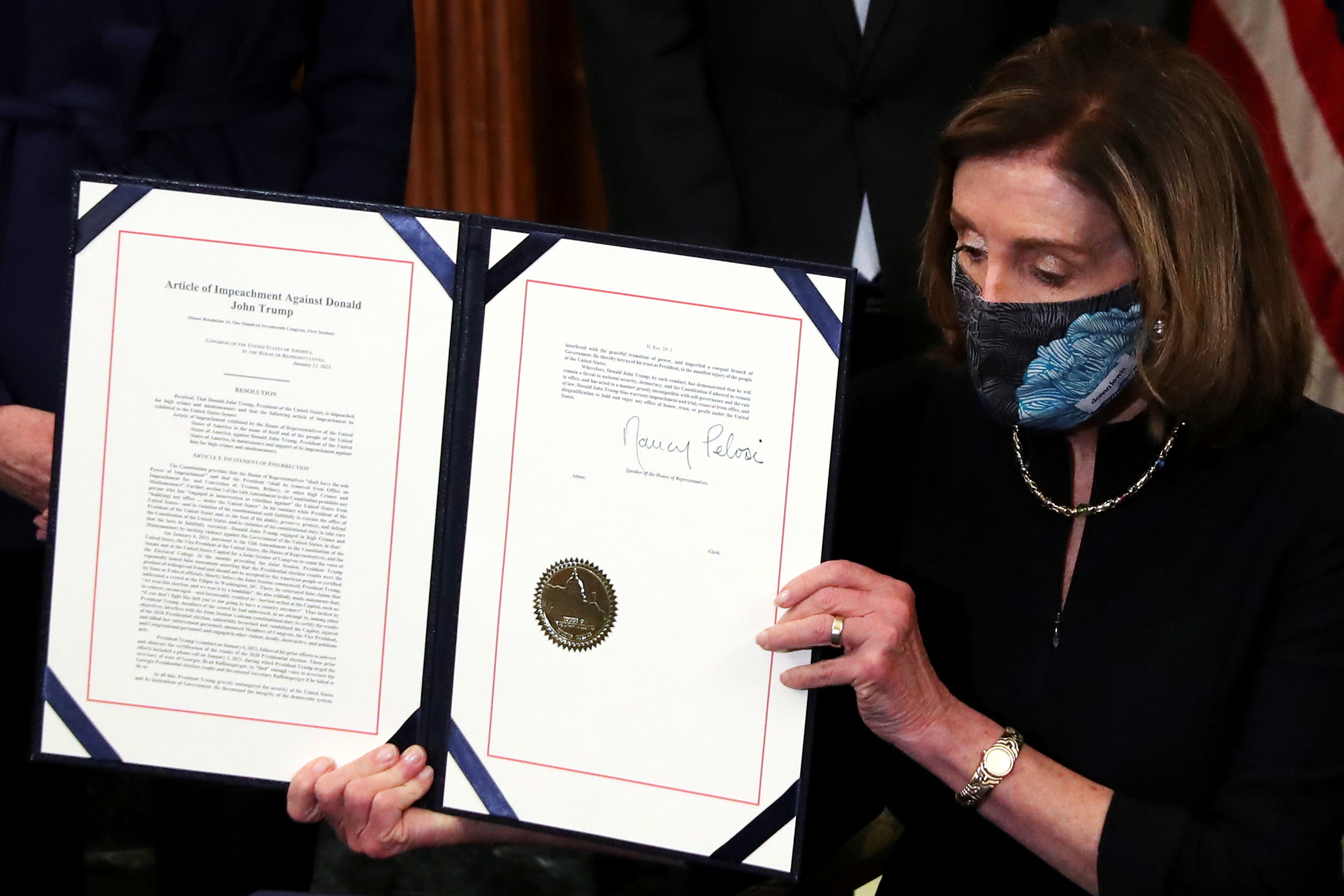 U.S. House Speaker Nancy Pelosi (D-CA) shows the article of impeachment against U.S. President Donald Trump after signing it in an engrossment ceremony, at the U.S. Capitol in Washington January 13, 2021.