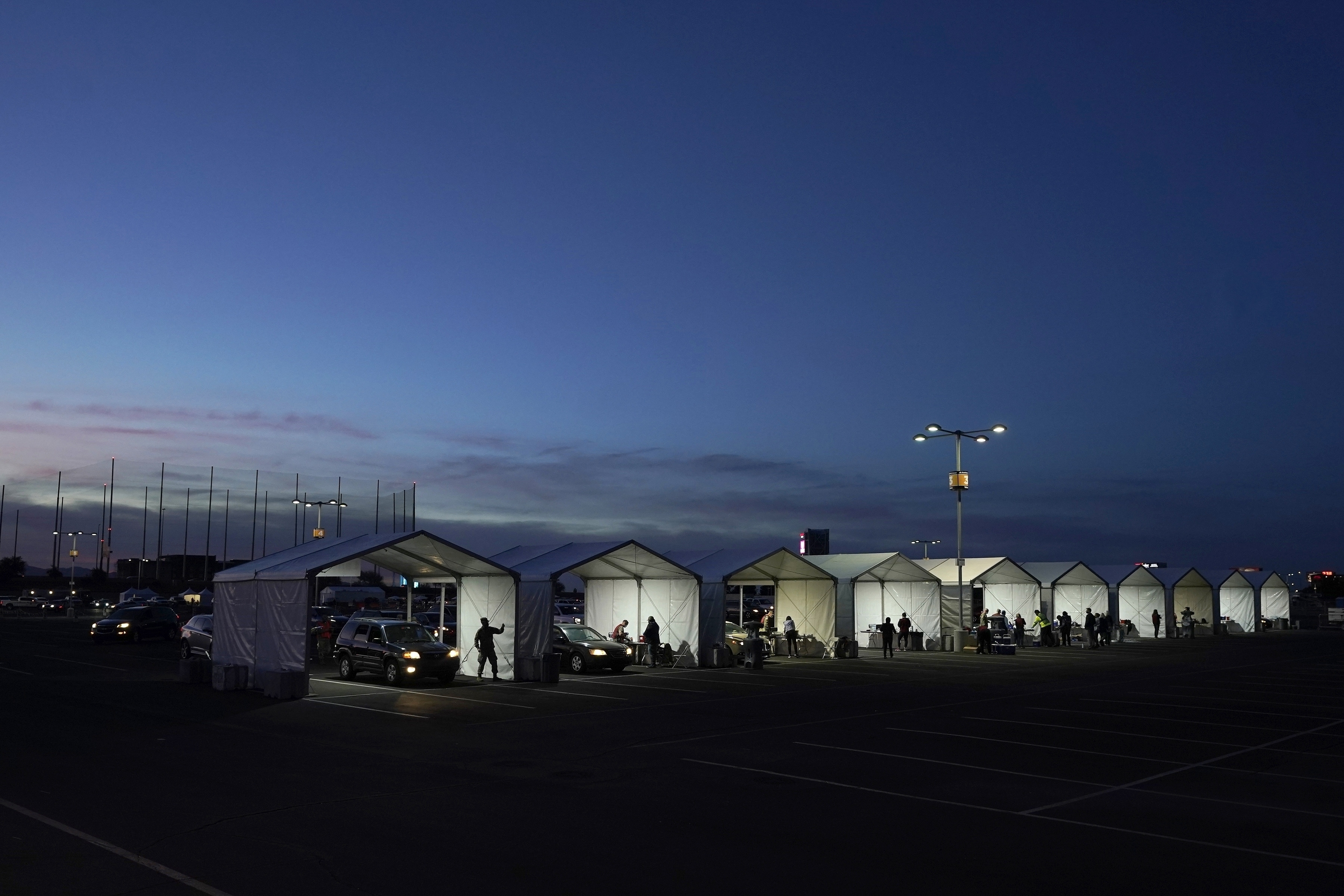 FILE - In this Jan. 12, 2021, file photo, several tents are set up so people who have registered can get their COVID-19 vaccinations as they drive-thru the parking lot of the State Farm Stadium in Glendale, Ariz. (AP Photo/Ross D. Franklin, File)
