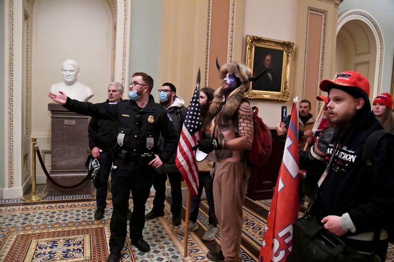 FILE PHOTO: Police speak to supporters of U.S. President Donald Trump, including Jake Angeli in the horn and fur costume, as they demonstrate on the second floor of the U.S. Capitol near the entrance to the Senate after breaching security defenses, in Washington, U.S., January 6, 2021.        REUTERS/Mike Theiler/File Photo