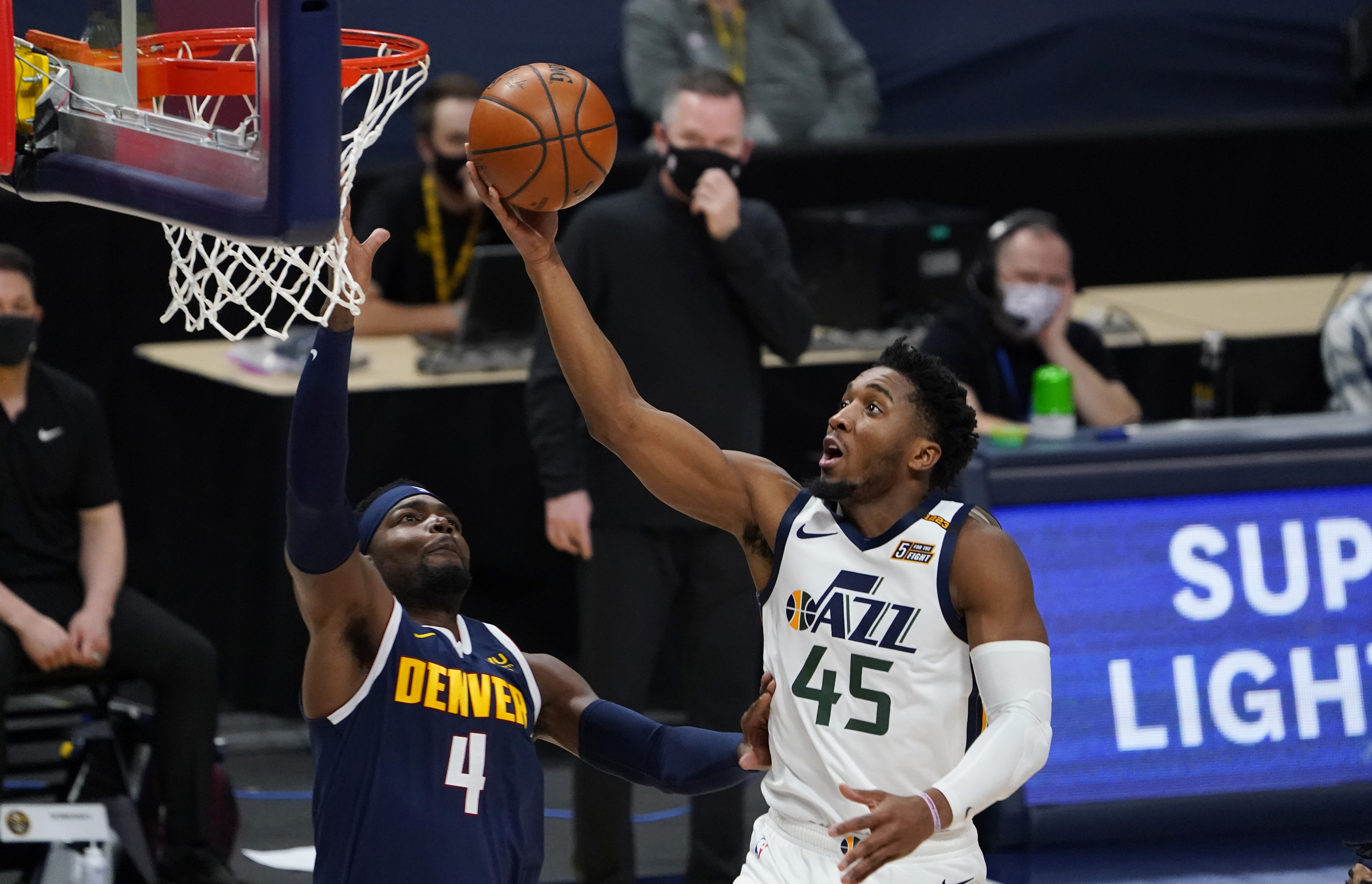 Utah Jazz guard Donovan Mitchell, right, drives to the basket as Denver Nuggets forward Paul Millsap defends in the first half of an NBA basketball game Sunday, Jan. 17, 2021, in Denver.