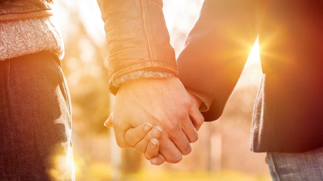 Closeup of loving couple holding hands while walking at sunset