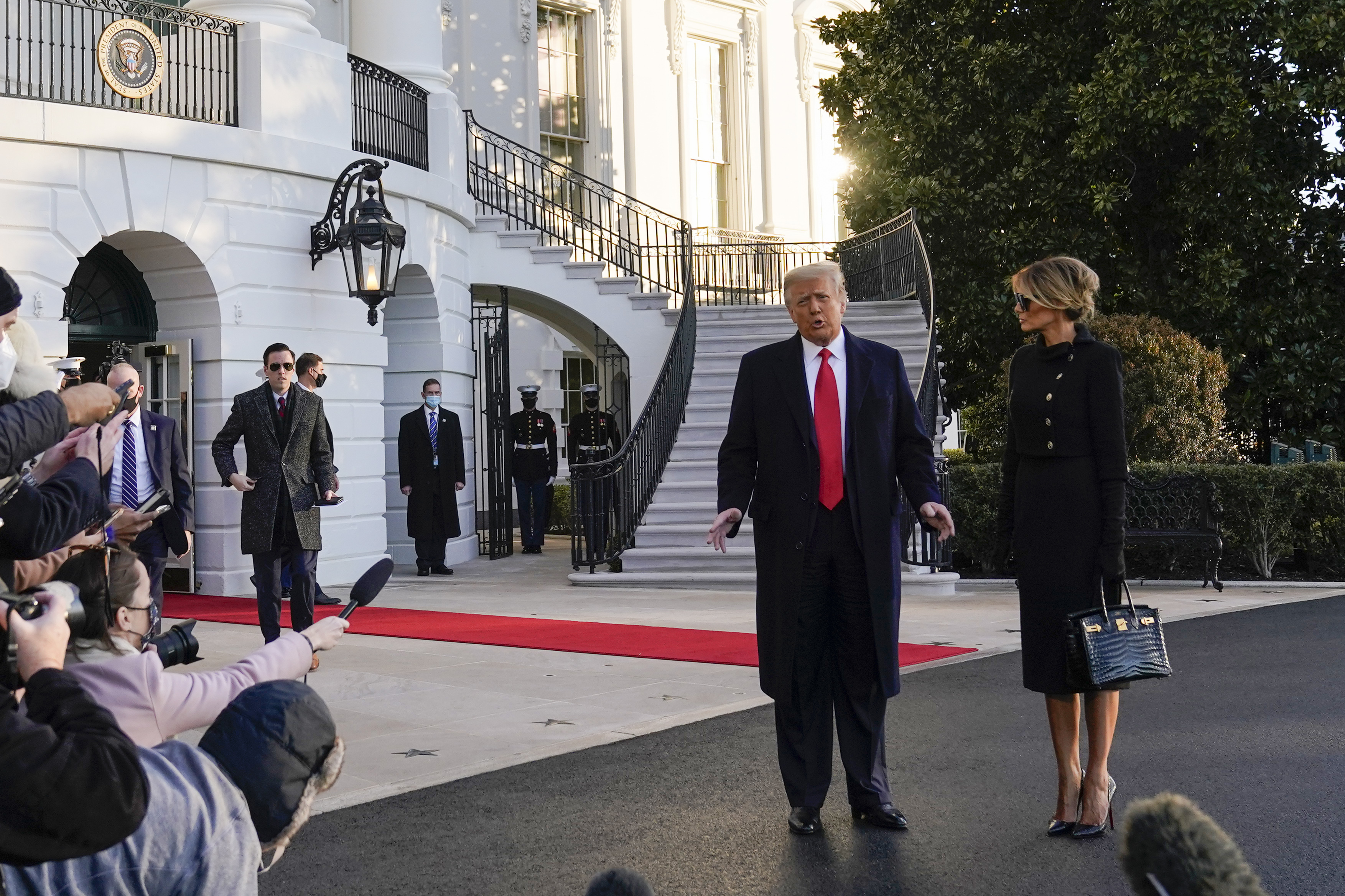 President Donald Trump and first lady Melania Trump stop to talk with the media as they walk to board Marine One on the South Lawn of the White House, Wednesday, Jan. 20, 2021, in Washington. Trump is en route to his Mar-a-Lago Florida Resort.