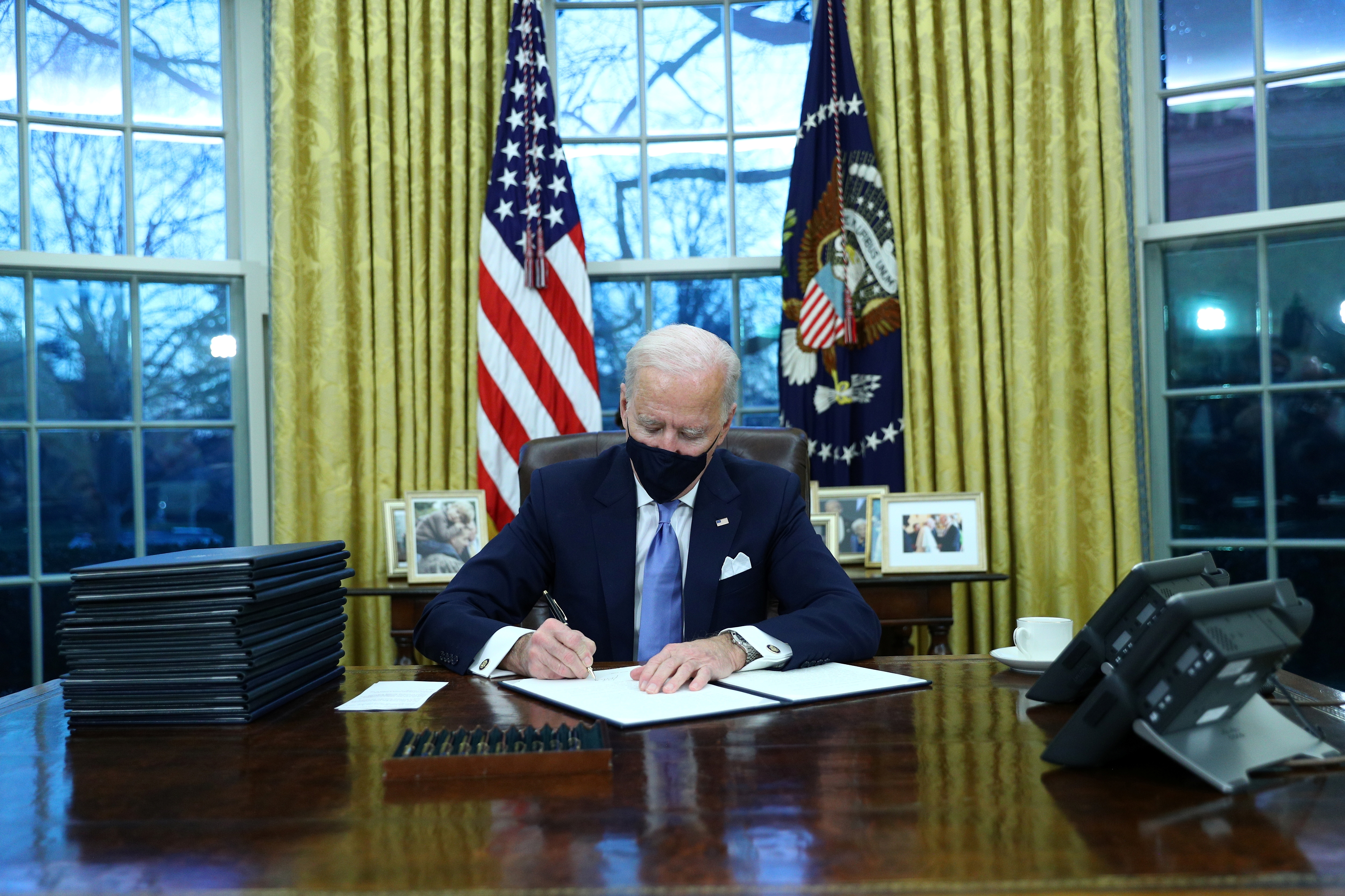 U.S. President Joe Biden signs executive orders in the Oval Office of the White House in Washington, after his inauguration as the 46th President of the United States, U.S., January 20, 2021.