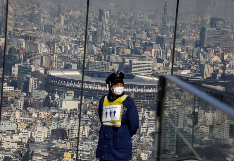 The National Stadium, the main stadium of Tokyo 2020 Olympics and Paralympics, is seen behind a security guard ahead of the six-months countdown to the Tokyo Olympics that have been postponed to 2021 due to the coronavirus disease (COVID-19) outbreak, at an observation deck in Tokyo, Japan January 22, 2021. REUTERS/Issei Kato