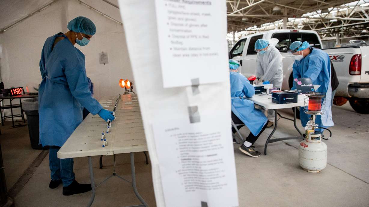 Utah National Guard Pfc. Noah Filoso, left, keeps track of timers on COVID-19 rapid tests at the Fairpark in Salt Lake City on Saturday, Jan. 23, 2021.