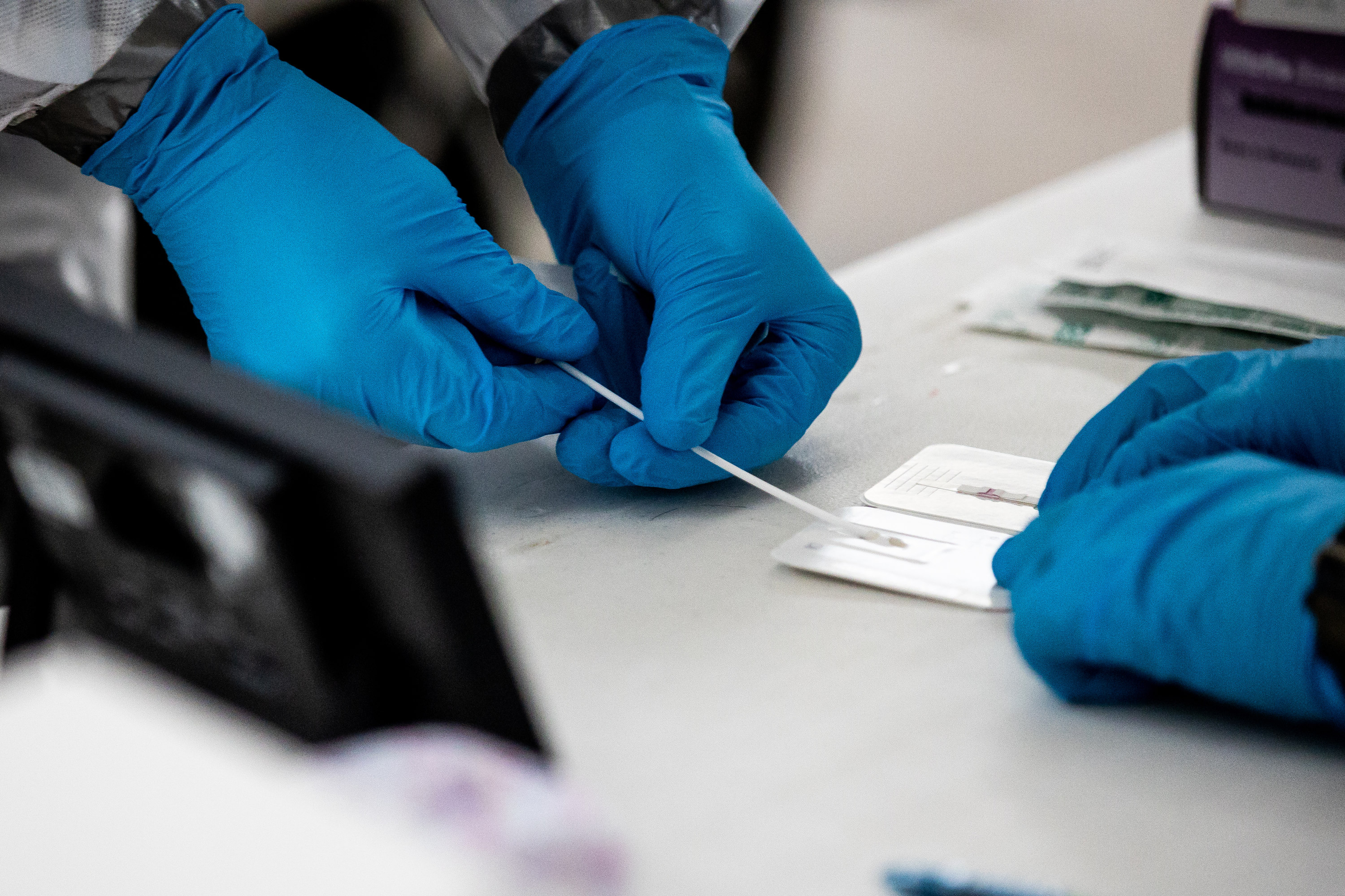Utah National Guard Master Sgt. Jaime Phair, left, hands off a swab after using it for a COVID-19 rapid test at the Fairpark in Salt Lake City on Saturday, Jan. 23, 2021.