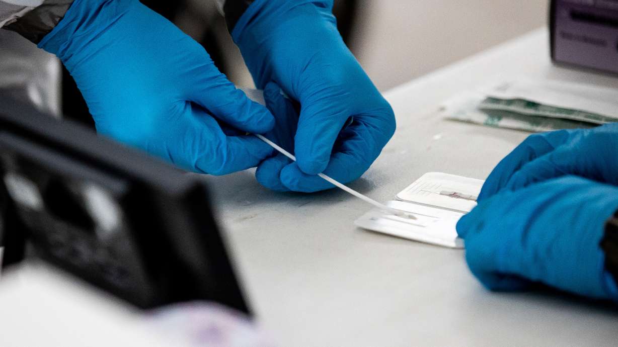 Utah National Guard Master Sgt. Jaime Phair, left, hands off a swab after using it for a COVID-19 rapid test at the Fairpark in Salt Lake City on Saturday, Jan. 23, 2021.