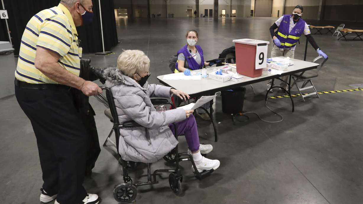 Richard and Joyce Durrant walk to station nine where Megan Boren, center, and Terry Begay, both Salt Lake County Health Department advanced EMTs, are waiting to give them their first dose of the COVID-19 vaccine at the countyâ??s mass vaccination site at the Mountain America Expo Center in Sandy on Monday, Jan. 18, 2021.