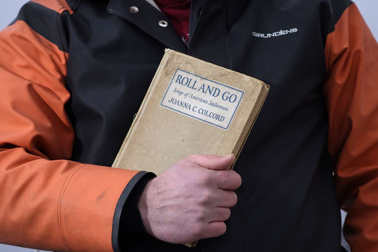 Bennett Konesni holds a book of sea shanties Thursday, Jan. 28, 2021, in Belfast, Maine. Work songs have helped sailors on long ocean journeys to break up the tedium. The genre is seeing a global revival among people bored and isolated by the coronavirus pandemic.